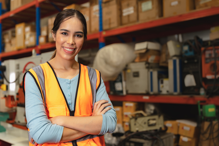 Woman smiling, standing in a warehouse