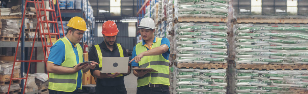 Three men in a warehouse discussing inventory